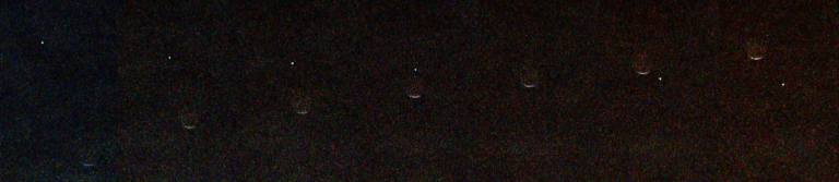 Composite of seven images showing a tiny bright dot representing Earth passing behind the dark crescent shape of the Martian moon Phobos against a black background.