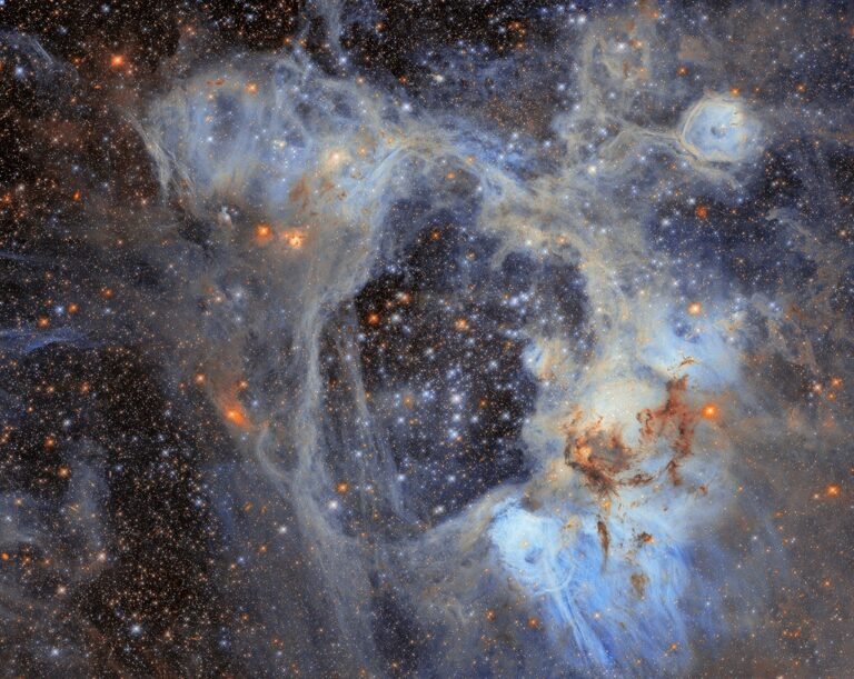 Hubble Space Telescope image of the N44 nebula in the Large Magellanic Cloud, showing a dark central superbubble surrounded by glowing blue and orange nebulosity and thousands of stars